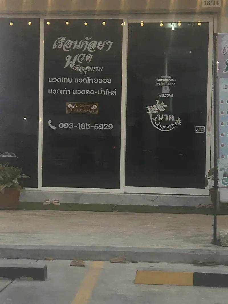 หน้าร้านยามค่ำ เวลาเปิด 09:00–21:00 บนกระจก / The shopfront in the evening, with opening hours on the glass